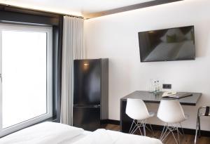 AichstettenAI Hotel by WMM Hotels的配有冰箱和桌椅的客房