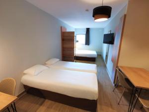 托尔西托尔西公寓式酒店的小房间设有两张床、一张桌子和一张书桌