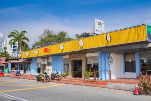 峇都丁宜JMA FERRINGHI BEACH HOTEL的停在前面的黄色建筑,有摩托车
