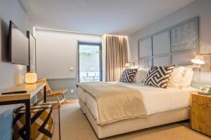 波尔图Pur Oporto Boutique Hotel by actahotels的一间卧室配有一张床、一张书桌和一个窗户。
