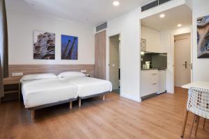 巴塞罗那奥古斯塔公寓式酒店的一间带白色大床的卧室和一间厨房
