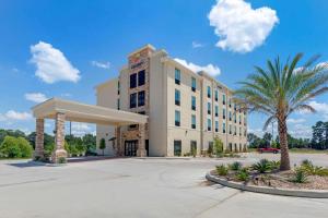西门罗Comfort Suites West Monroe near Ike Hamilton Expo Center的一座白色的大建筑,前面有棕榈树