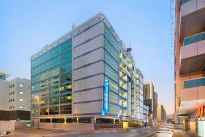 迪拜Howard Johnson Plaza by Wyndham Dubai Deira的城市街道上一座高大的玻璃建筑