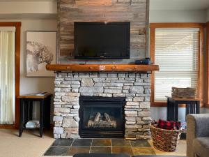 潘诺拉马Panorama Springs的客厅设有石制壁炉和平面电视。