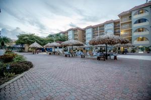棕榈滩Eagle Aruba Resort的酒店前方设有带桌子和草伞的庭院。