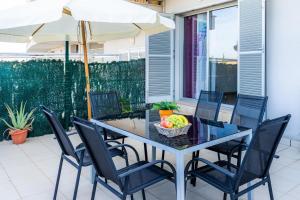 阿尔库迪亚Acogedor apartamento en Alcudia的餐桌、椅子和遮阳伞