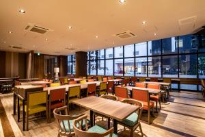 松本Tabino Hotel lit Matsumoto的餐厅设有桌椅和大窗户。