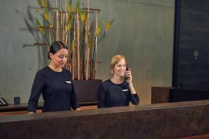 阿姆斯特丹Inntel Hotels Amsterdam Landmark的两个女人站在镜子前,用手机说话