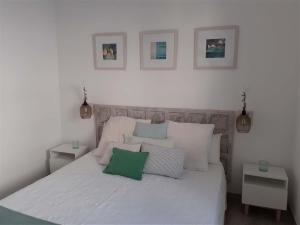 阿瓜阿马加Precioso Apartamento a 20 metros del mar的卧室配有一张白色床,墙上挂有三张照片
