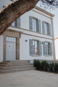 莱塞比耶Hôtel-Restaurant Villa Métis的白色的房子,设有灰色百叶窗和楼梯