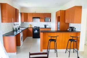 利隆圭Modern & secure apartment in Area 43 Lilongwe - self catering的厨房配有木制橱柜和2个酒吧凳
