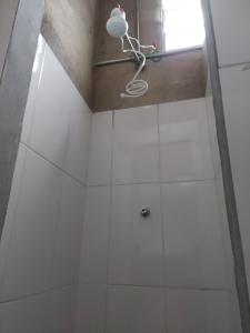 新利马Pousada Vila da Serra - Quarto do Amor的配有白色瓷砖和灯的淋浴间