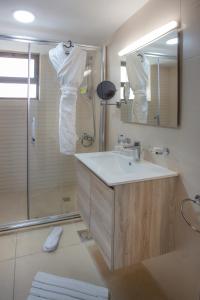 安曼Triple A Hotel Suites的浴室配有盥洗盆和带镜子的淋浴