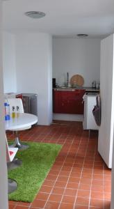 乌埃克尔明德老镇公寓的厨房配有白色的桌子和绿色的地毯。