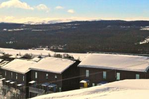 菲奈斯达伦Ski Lodge Funäsdalen的一座被雪覆盖的建筑,背景是群山