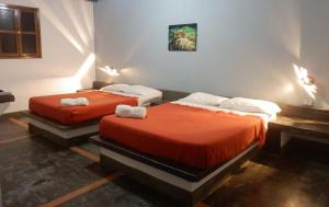 Paraguachi卡萨拉斯特里尼塔里阿斯宾馆的红色床单的客房内的两张床