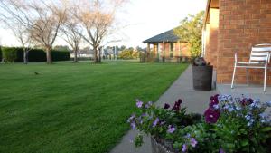 基督城Northwood Motor Lodge的一座房子旁边的院子,里面摆放着椅子和鲜花