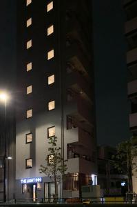 东京The Light Inn - Vacation STAY 94696的一座高大的建筑,晚上在前面有标志