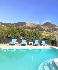 皮萨拉Casa rural la Estrella的一组椅子和一个享有山景的游泳池