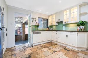 珀斯Layman Park Villa的厨房配有白色橱柜和瓷砖地板。