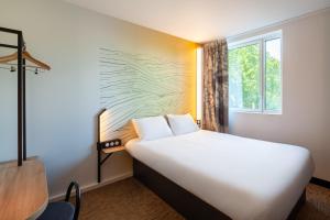 布瓦达西B&B HOTEL Bois d'Arcy Saint Quentin en Yvelines的卧室设有一张白色大床和一扇窗户。
