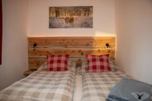 GrossvolderbergAppartement 'Oachkatzl'的一间卧室配有两张带红色和白色拼盘枕头的床