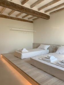 瓜斯塔拉La Pervinca - Ospitalità, Natura, Cura的配有白色墙壁和木地板的客房内的两张床