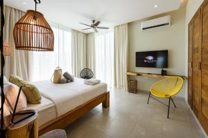 拉斯特拉纳斯Saman Boutique Hotel的一间卧室配有床、电视和黄椅