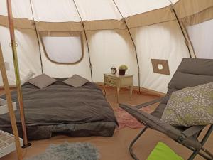 NeerpeltNatuur-like Glamping in Bosland的一间卧室配有一张床铺,帐篷内提供一把椅子