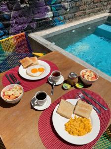 圣玛尔塔Imagine hostel的一张桌子,上面有早餐盘,在游泳池边