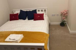 威布里治Luxurious & Cosy Apartment in Surrey的一间卧室配有一张带红色和蓝色枕头的床