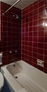 温尼伯柯蒂斯戈登汽车旅馆的红色瓷砖浴室设有白色浴缸