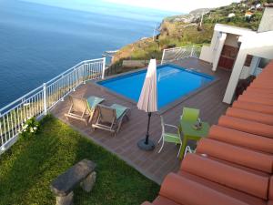 阿科达卡列塔CASA SOL E VISTA 2的一座带椅子和遮阳伞的游泳池,毗邻大海