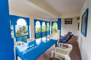 奈尼塔尔Seclude Ramgarh Arthouse的窗户里摆放着蓝色的桌子和椅子