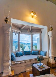 奈尼塔尔Seclude Ramgarh Arthouse的靠窗的座位,房间带蓝色枕头