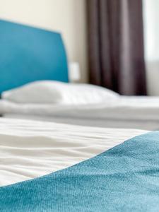 维尔纽斯"AVA" apgyvendinimo įstaiga的一张带白色床单和蓝色毯子的床