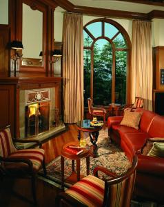 西姆拉Wildflower Hall, An Oberoi Resort, Shimla的客厅设有红色的沙发和壁炉
