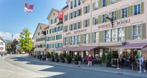 布鲁嫩Weisses Rössli Swiss Quality Hotel的街上的一座建筑,人们在人行道上走