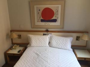 贝洛奥里藏特Flat Golden Plaza - Lourdes的卧室配有白色床、两个床头柜和电话