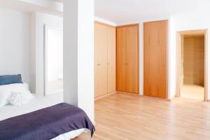 略夫雷加特河畔奥斯皮塔莱特费拉复式公寓的卧室设有白色的墙壁、一张床和木制橱柜。