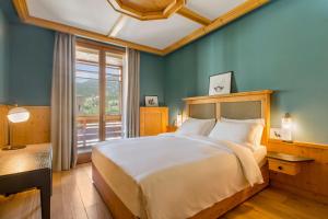 科尔蒂纳丹佩佐Radisson Residences Savoia Palace Cortina d’Ampezzo的一间卧室设有一张大床和一个大窗户
