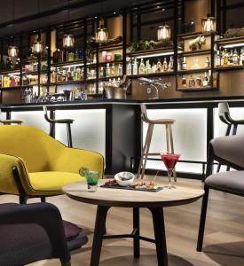 鲁瓦西昂法兰西INNSiDE by Meliá Paris Charles de Gaulle Airport的酒吧设有黄色椅子和桌子,并备有饮料