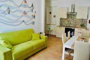 诺托玛丽娜Casa vacanze Almàsalo的一间带绿色沙发的客厅和一间厨房