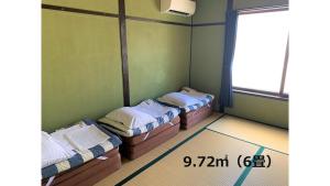 松江市Matsue Guesthouse的一间设有三张床的房间,设有窗户