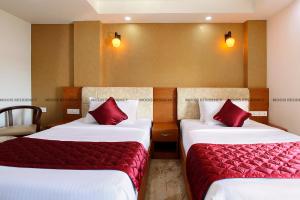 坎努尔Moois Residency的两张位于酒店客房的床铺,配有红色枕头