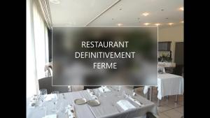 克吕斯Hôtel 4C的带有白色桌椅的餐厅标志