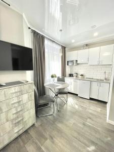 伊尔平Элегантная квартира-студия ЖК Рич Таун, Ирпень的厨房配有白色橱柜、桌子和电视。
