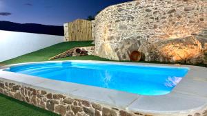 HinojalesCasa Rural Sierra Tórtola 2的石头墙前的蓝色游泳池