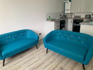 DalmuirThe Cochno Flat, Clydebank的带厨房的客房内的2张蓝色沙发