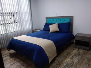 NobsaCasa Bertha Hotel y Servicios SAS的卧室里一张带蓝色床单和蓝色床头板的床